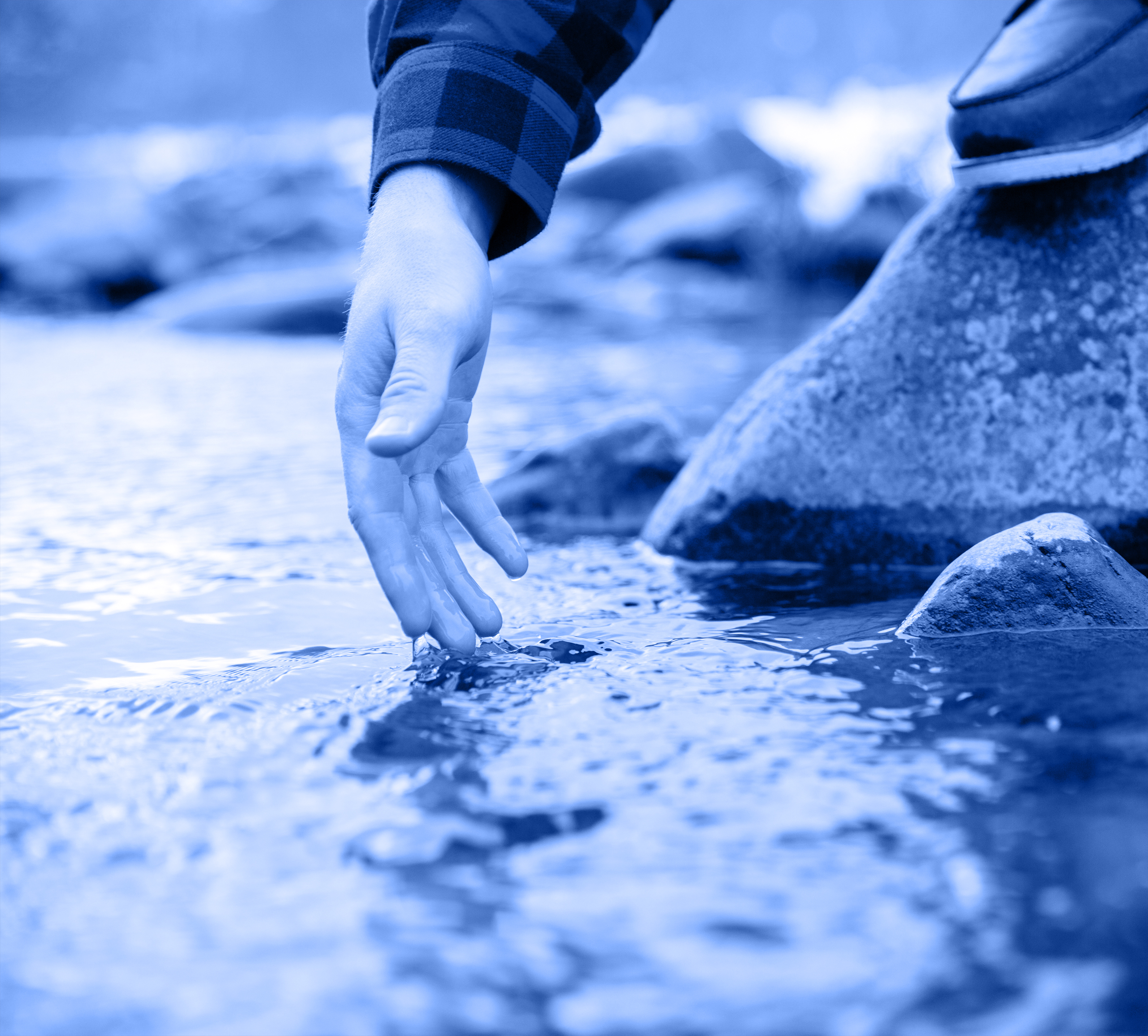 Hand being dipped into stream or lake